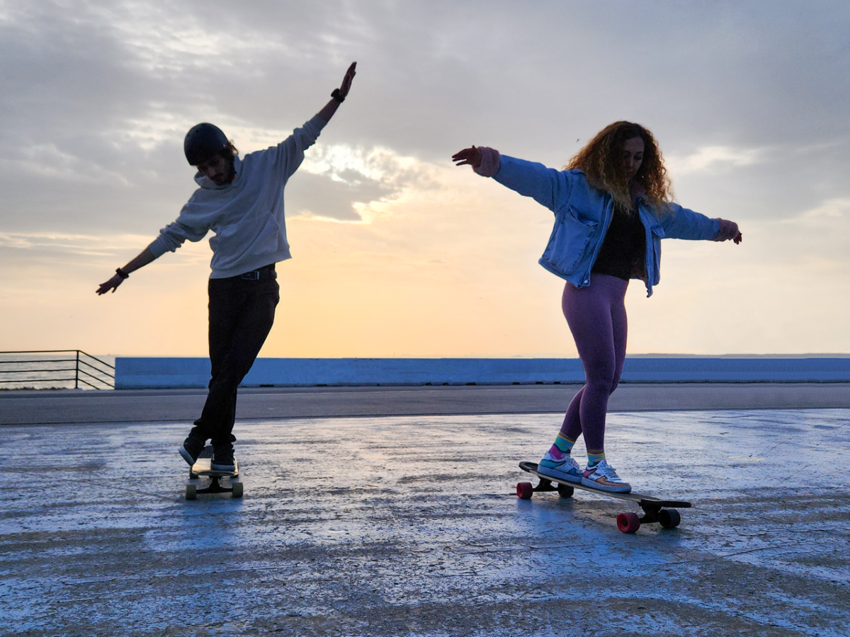Respect et Charisme Two young adults skateboarding gracefully on a seaside promenade at sunset in İstanbul, Türkiye.